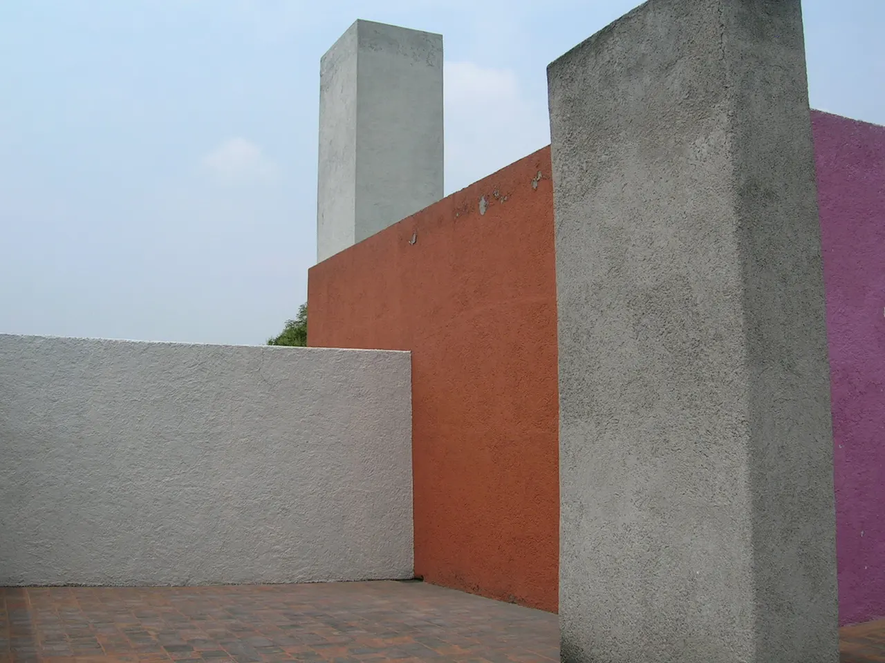 Orange, pink and grey walls on the roof terrace of Casa Luis Barragán, the white water tower behind them